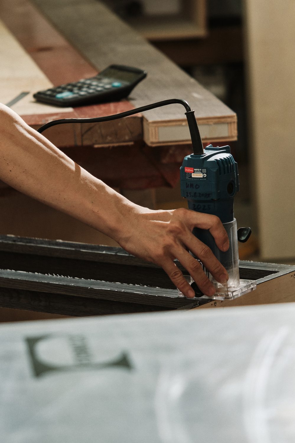 unOwned at work — hands routing a piece of joinery, the tool marked UNO