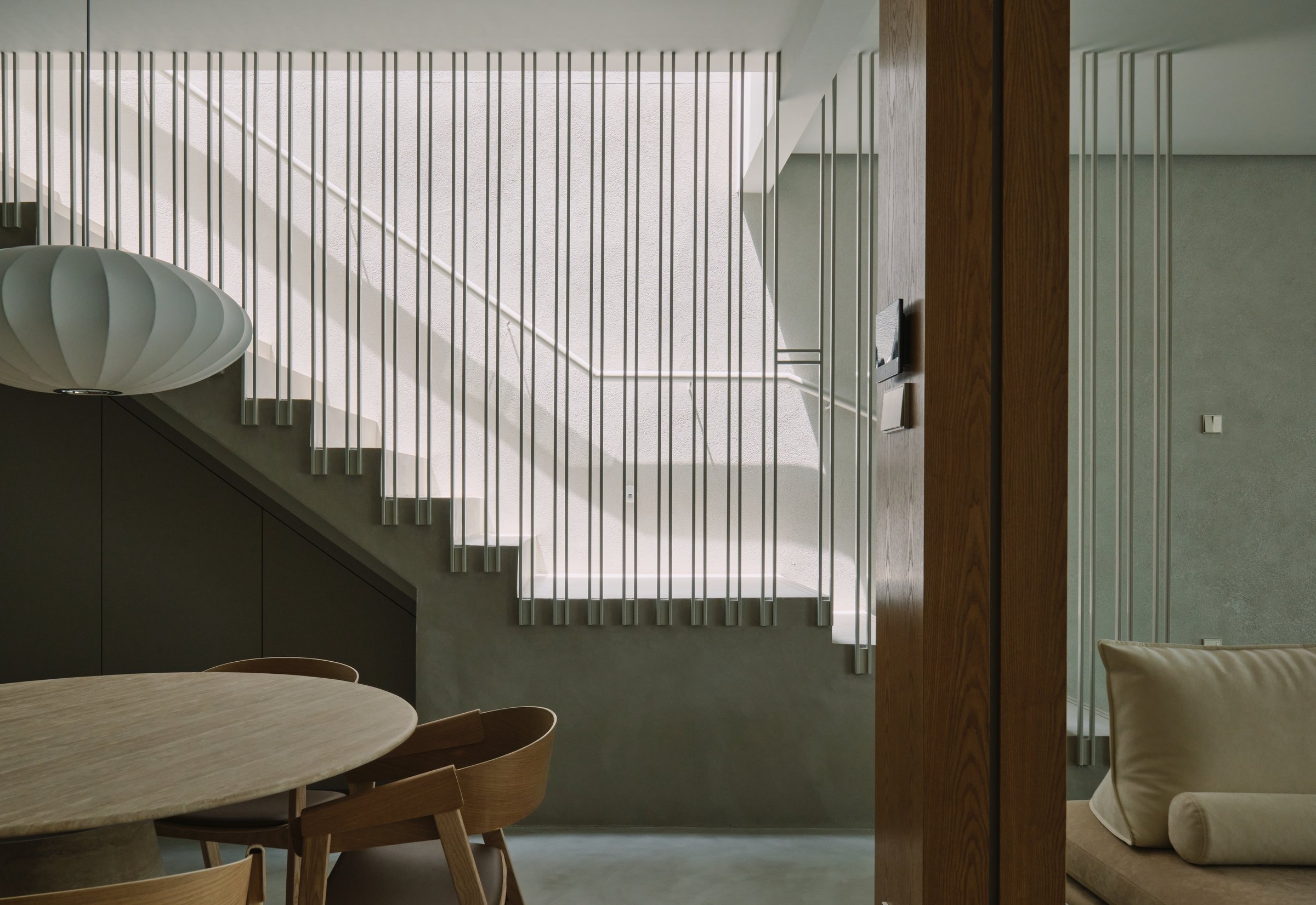 A finished UNO interior at rest — late light across a plaster wall, balustrade rods catching the day