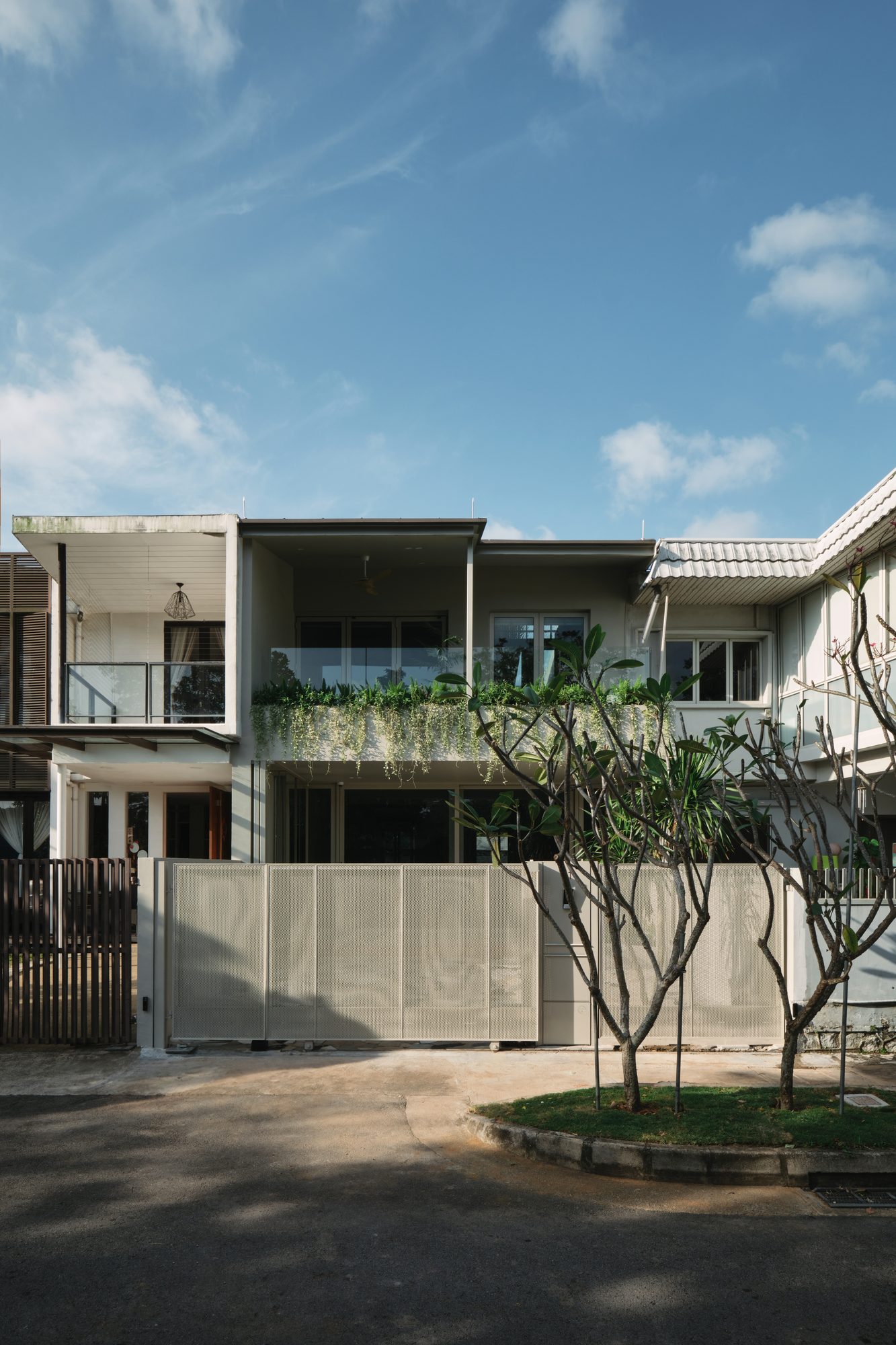 The front of the house, the perforated metal gate closed in afternoon light