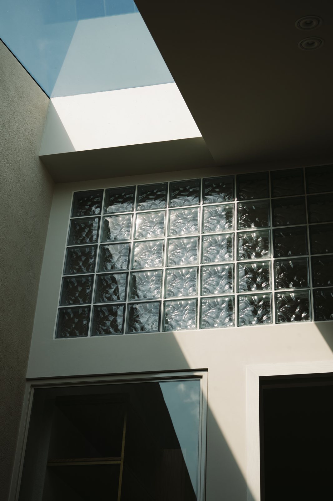 A skylight above a glass block wall, light moving through the blocks